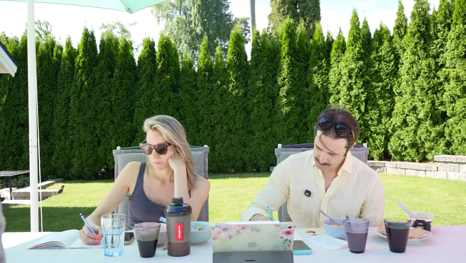 Erika and Martin writing in notebooks at a garden table
