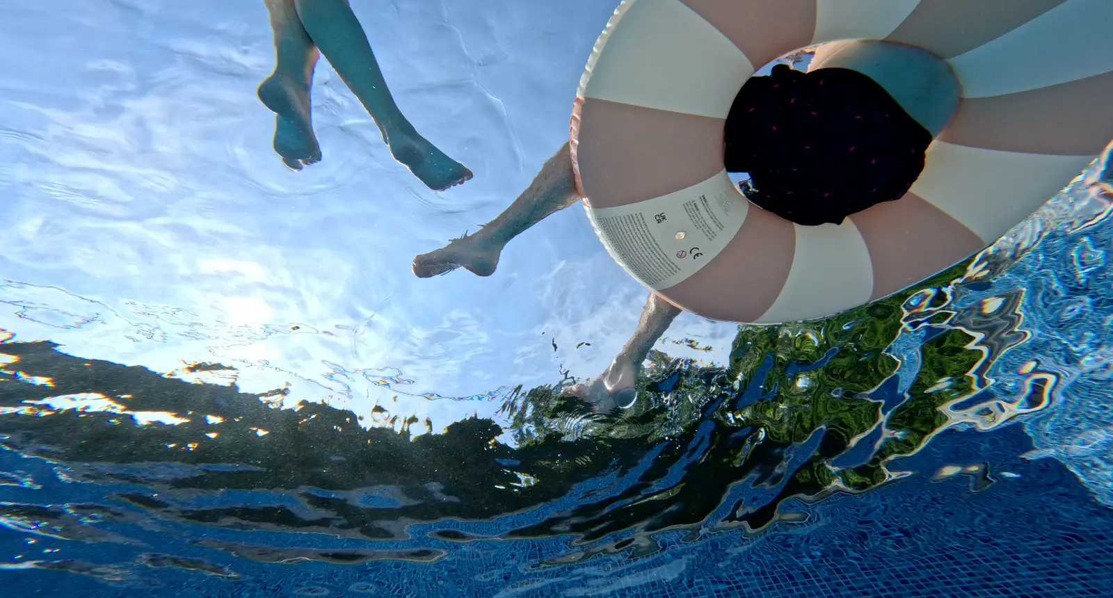 Underwater view of two readers floating in swim rings above